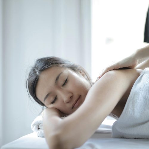 Asian woman enjoying a relaxing body massage at a spa to unwind and rejuvenate.