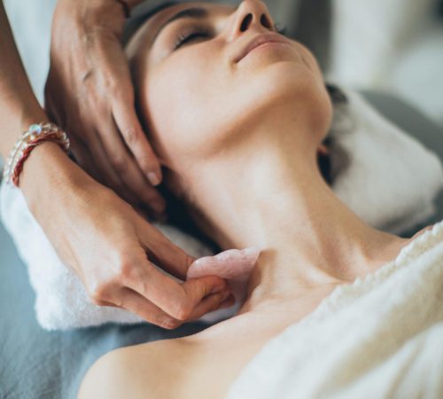 Woman receiving a relaxing gua sha massage in a calm spa setting for wellness and beauty.