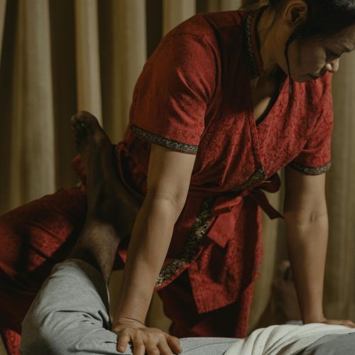 Professional Thai massage session with therapist applying pressure on client's leg for relaxation.